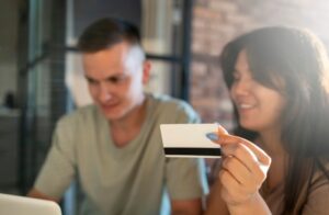 Homme et femme utilisant un ordinateur portable pour faire des achats en ligne avec une carte de crédit- greffe de cheveux en Turquie
