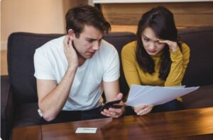 Couple assis sur un canapé discutant avec des documents financiers dans un salon