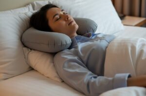 Personne utilisant un oreiller de nuque pour dormir après une greffe de cheveux et protéger la zone greffée.